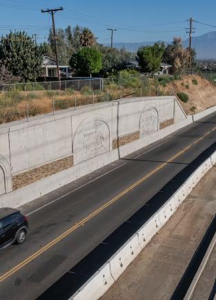 Hamner Avenue bridge car driving past new sound wall etched with horses.